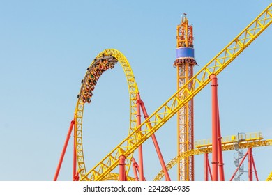 Roller coaster up down turn and a passing loop feint, spiral train of trolleys tends to go down, tower with free fall chairs nearby