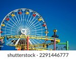 roller coaster, ferris wheel and a hammer in a colorful amusement park on a clear day with blue sky, a landscape from theme park in santa monica beach, los angeles, california, usa, november 2022