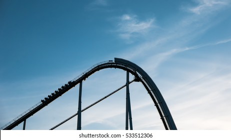 A Roller Coaster Going Up The Tracks Against A Blue Sky