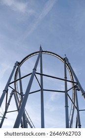 A roller coaster with a large white structure in the middle. The sky is blue and clear