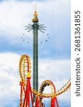 Roller coaster and tower swing ride at Vienna’s Prater amusement park, captured on a dramatic summer day with vivid colors and thrilling motion.