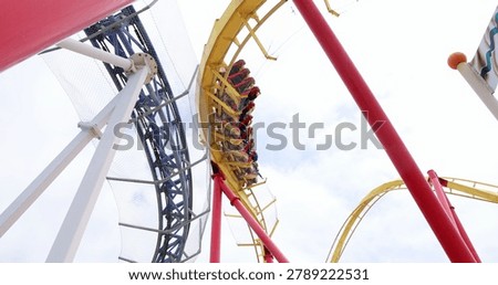 Roller coaster train speeding through loop on yellow track at amusement park. adrenaline, amusement park, thrill ride, entertainment, summer vacation, extreme fun.