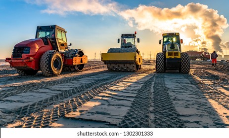 roller compacts soil in embankment on the road's construction. sand consolidation on road-building. Compactor driving on sandy. wheel marks on the sand. hard work. transportation of sand by trucks - Powered by Shutterstock