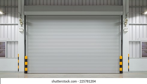 Roller Door Or Roller Shutter Using For Factory, Warehouse Or Hangar. Industrial Building Interior Consist Of Polished Concrete Floor And Closed Door For Product Display Or Industry Background.