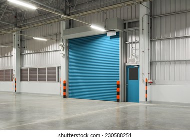 Roller Door Or Roller Shutter Using For Factory, Warehouse Or Hangar. Industrial Building Interior Consist Of Polished Concrete Floor And Closed Door For Product Display Or Industry Background.