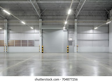 Roller Door Or Roller Shutter Using For Factory, Warehouse Or Hangar. Industrial Building Interior Consist Of Polished Concrete Floor And Closed Door For Product Display Or Industry Background.