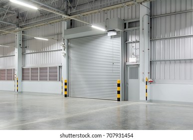 Roller Door Or Roller Shutter Using For Factory, Warehouse Or Hangar. Industrial Building Interior Consist Of Polished Concrete Floor And Closed Door For Product Display Or Industry Background.