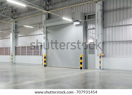 Roller door or roller shutter using for factory, warehouse or hangar. Industrial building interior consist of polished concrete floor and closed door for product display or industry background.