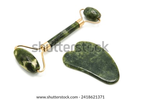 Roller for face massage and gua sha massager isolated on white background. Set of massage. Green jade stone for face and body care. Copy space. Top view.
