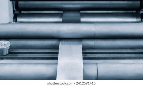 Roller feed unit of continuously high speed metal sheet strip shape beam roll forming machine for manufacturing process in industrial. industry metal processing concept blue tone background