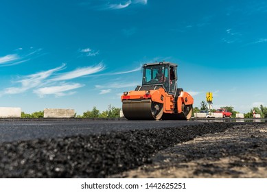 Roller rolling fresh hot asphalt on the new road. Road construction. - Shutterstock ID 1442625251