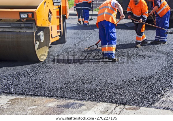 Roller and workers on asphalting and repair of\
city streets