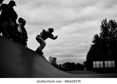 Rollerblader in aggressive inline skates grinding on rampa in outdoor skate park. Extreme sports athlete concept for brave and strong people.