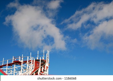 rollercoaster with white puffy clouds and a blue sky
