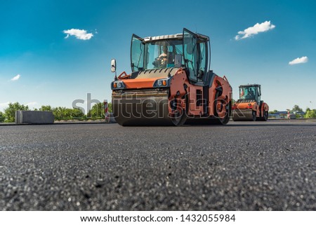 Rollers rolling fresh hot asphalt on the new road. Road construction.