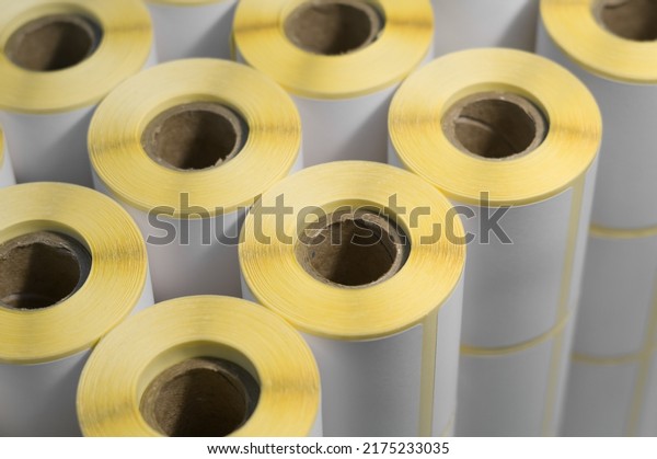 Rollers with a white\
self-adhesive label for printing labeling information. Ribbon with\
white label on cardboard spools. Products of the printing house.\
Selective focus