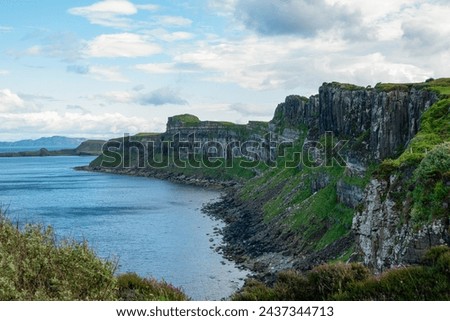 Rolling clouds over rugged craggy ocean shoreline of picturesque Isle of Skye. Amazing scenery with rocky cliffs rising above wavy ocean and changing weather conditions on a famous Scottish island.