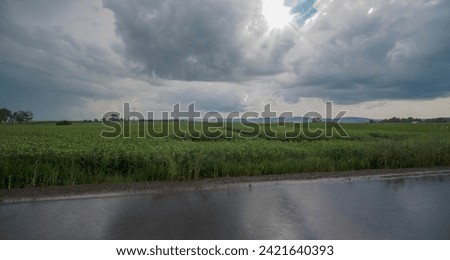 Rolling dark rain clouds over fields in the Holy Cross Mountains on a June afternoon. Swietokrzyskie fields in the last days of spring, just after the rain, the sun trying.