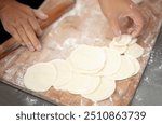 Rolling dumpling wrappers in kitchen