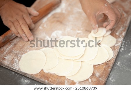 Rolling dumpling wrappers in kitchen