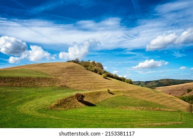 Rollende Grünlandschaft mit rundem Hügel auf blauem Himmel, Badberg, Kaiserstuhl, Deutschland.