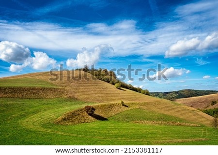 Rolling green grassland landscape with round hilltop against blue sky., Badberg, Kaiserstuhl, Germany.