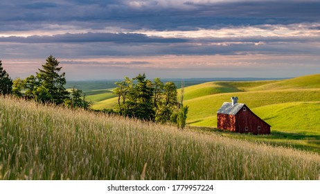 Rolling hills of farm fields and a red barn with tress