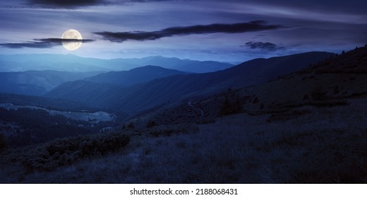 Rolling Hills And Grassy Meadows Of Carpathians. Chornohora Mountain Ridge In The Distance On A Summer Night With Clouds On The Sky In Full Moon Light