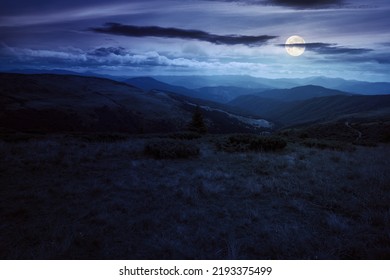 Rolling Hills And Grassy Meadows Of Carpathians. Chornohora Mountain Ridge In The Distance On A Summer Night With Clouds On The Sky In Full Moon Light