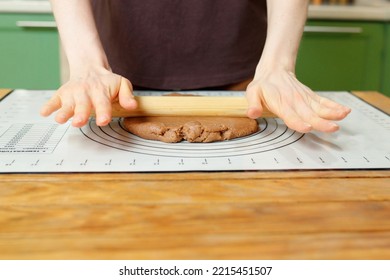 Rolling out gingerbread dough on a silicone baking mat on a wooden table with copy space. - Powered by Shutterstock