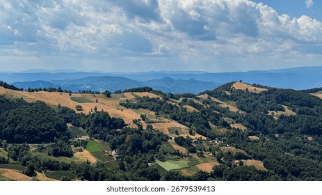 Rolling patchwork hills under a whimsical sky evoke an unexpected yearning for Lammas celebrations and rural escapades