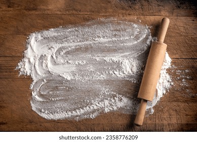 Rolling pin and flour as background  on wooden cutting board or kitchen table, top view, copy space. Baking or cooking concept. - Powered by Shutterstock