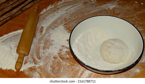 Rolling Pin And Kneaded Dough Are Waiting On The Wooden Table For The Next Stage Of Cooking.
