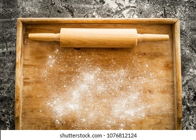 Rolling pin on empty pastry board sprinkled with flour. Kitchen scenery captured from above (top view, flat lay). Black chalkboard as background. Layout with free text (copy) space. - Powered by Shutterstock