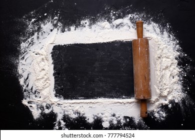 Rolling Pin And White Flour On A Black Textural Background. Free Space For Text. View From Above.