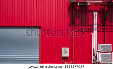 Rolling shutter door with Hvac air ventilation system with pipeline on red aluminum corrugated wall of industrial building