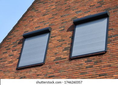 Rolling shutters brick house windows protection. Brick house with metal roller shutters on the windows.
