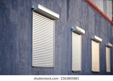 Rolling shutters, windows with closed roller shutters. House facade with window on first floor, security and protection concept. Selective focus