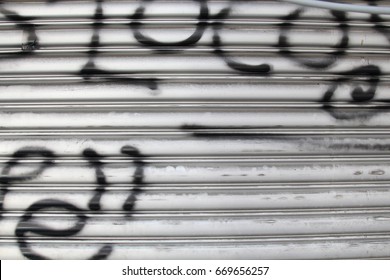 Rolling sliding shop door with vandalism sign of graffiti black spray paint 