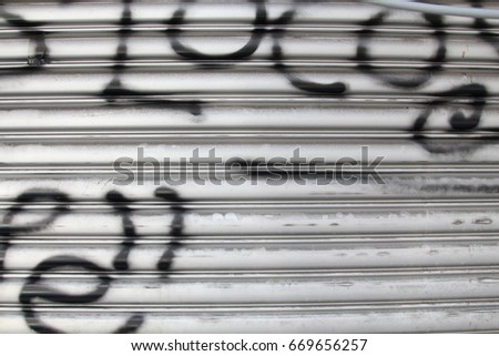 Rolling sliding shop door with vandalism sign of graffiti black spray paint 