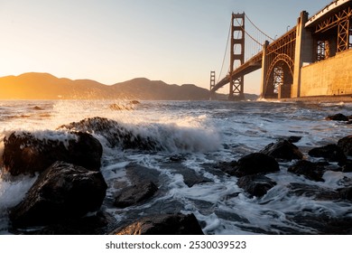 The rolling waves crashing onto the shoreline with Golden Gate Bridge in the background at sunset - Powered by Shutterstock