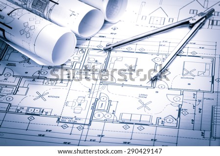 rolls of architecture blueprints and house plans on the table and drawing compass