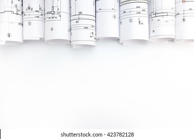 rolls of architecture blueprints and technical drawings on white background