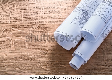 Rolls of blueprints on wooden oaken board construction concept 