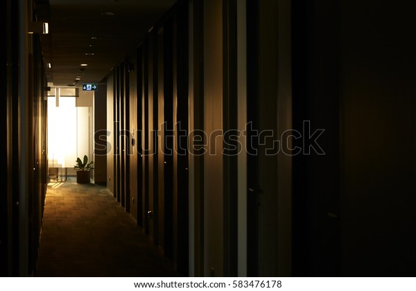 Rolls of empty dark\
office hallway at dawn