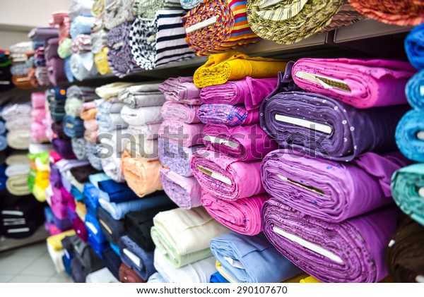 Rolls of fabric and textiles\
in a factory shop. Multi different colors and patterns on the\
market.