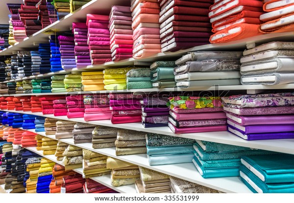 Rolls of fabric and textiles in a factory shop\
or  store or bazar. Multi different colors and patterns on the\
market. Industrial\
fabrics.