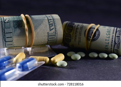 Rolls of money, Us dollars and prescription drugs on dark surface. - Powered by Shutterstock