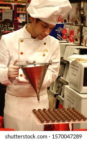 Roma, Italy - October 26, 2019: Young Worker Stuffing With Chocolate Round Pralines In A Lindt Store. Lindt & Sprungli AG Is A Swiss Chocolatier And Confectionery Company