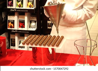 Roma, Italy - October 26, 2019: Young Worker Stuffing With Chocolate Round Pralines In A Lindt Store. Lindt & Sprungli AG Is A Swiss Chocolatier And Confectionery Company